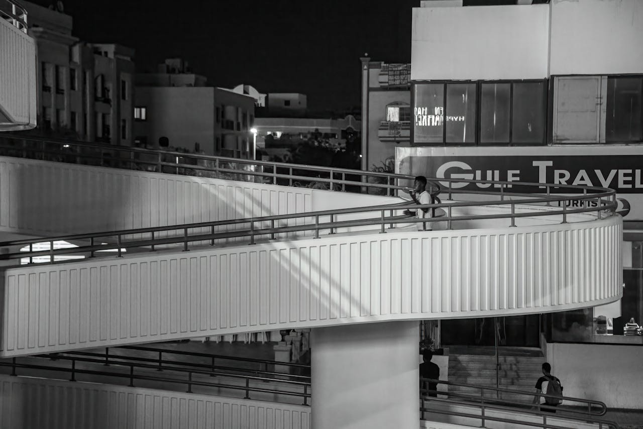 Black and white photo of a modern footbridge in Dubai at night.